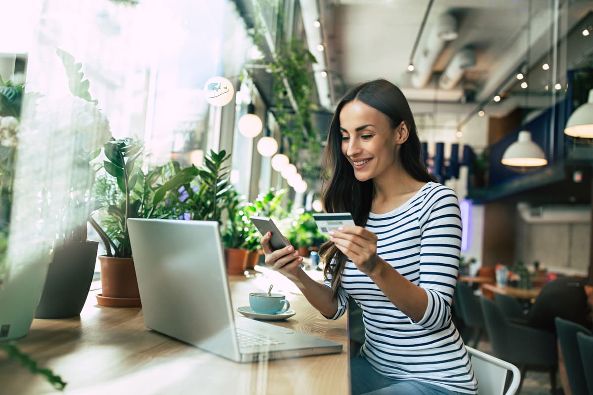 a woman is sitting at a table with a laptop and a credit card .